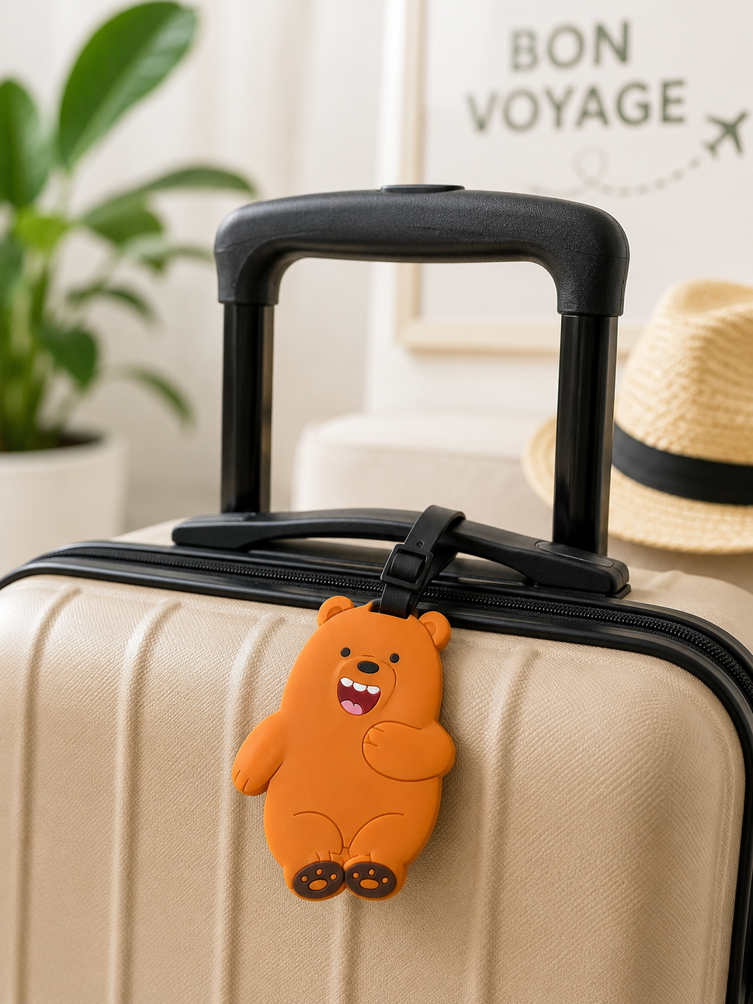 Orange bear shaped silicone luggage tag attached to a beige suitcase handle
