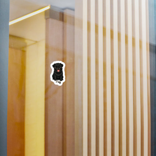 A small die-cut sticker of a black dog with a red tongue, shown on a glass door or window with a modern interior background of vertical wooden slats.