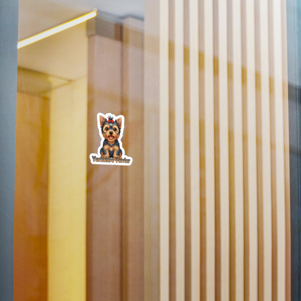 A small die-cut sticker featuring a cartoon Yorkshire Terrier wearing a crown with the text 'Yorkshire Terrier' underneath, shown applied to a glass door or window with a blurred indoor background.