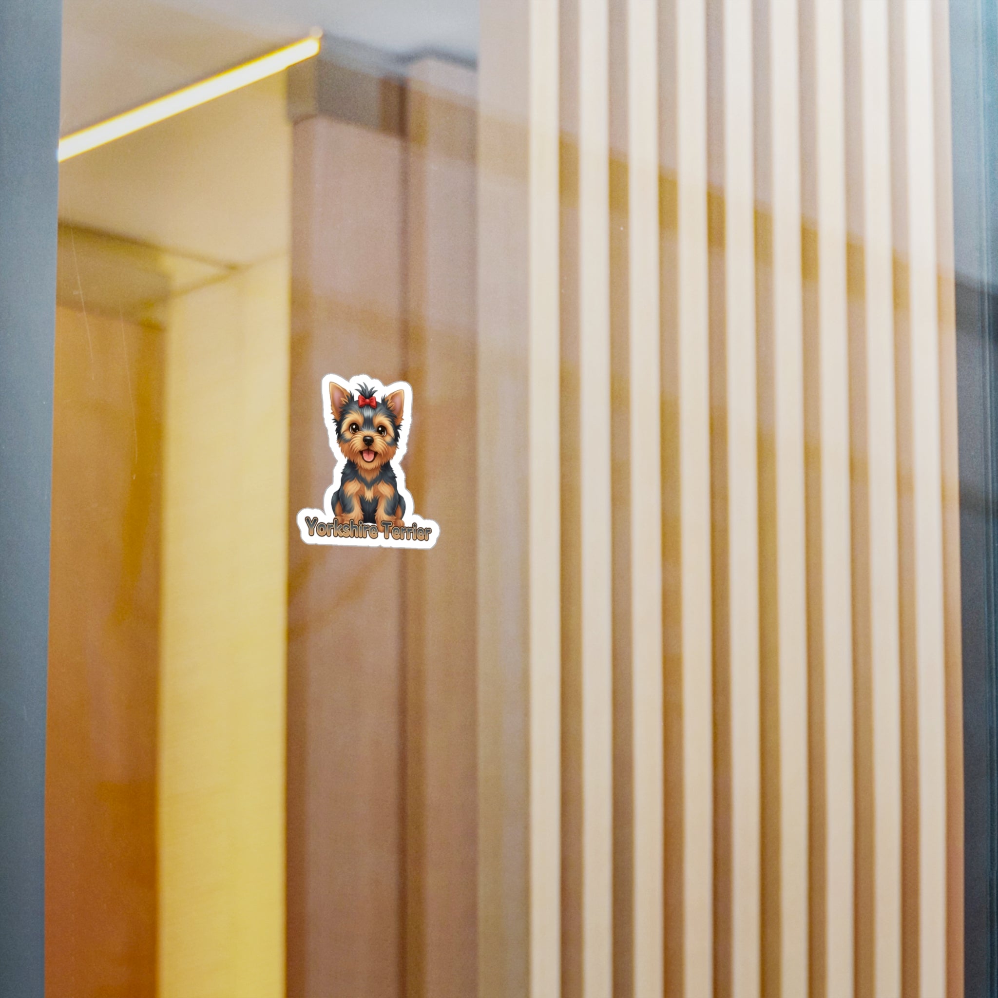 A small die-cut sticker featuring a cartoon Yorkshire Terrier wearing a crown with the text 'Yorkshire Terrier' underneath, shown applied to a glass door or window with a blurred indoor background.